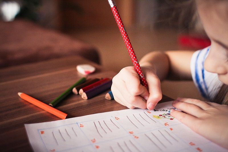enfant-qui-ecrit-dans-un-livre-d-activites