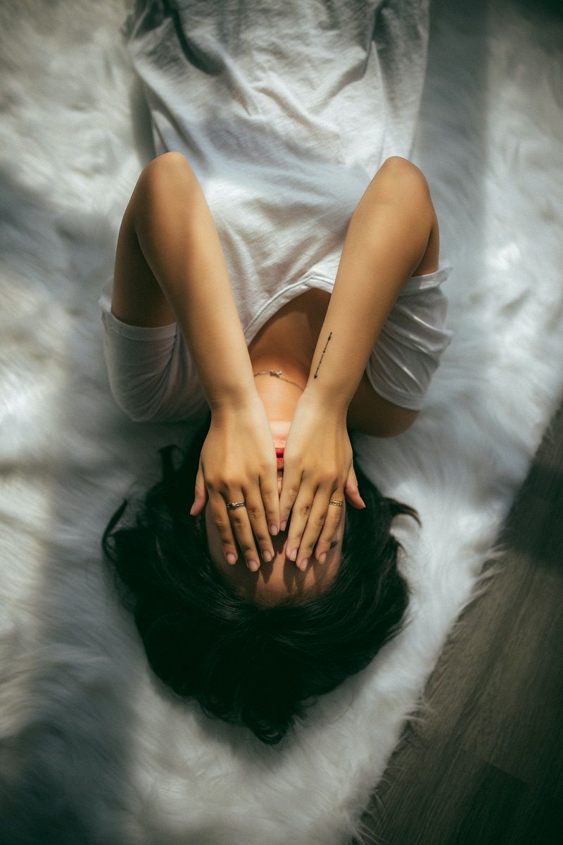 femme-allongee-avec-les-mains-sur-le-visage