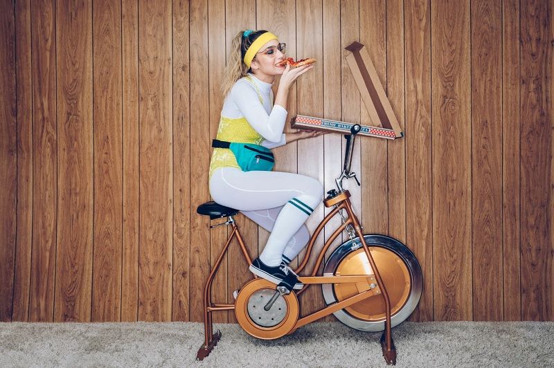 femme-manger-pizza-sur-velo-appartement