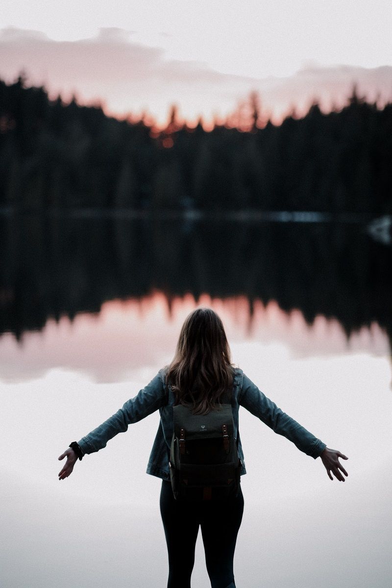 femme-seule-bras-ouverts-devant-un-paysage-lac