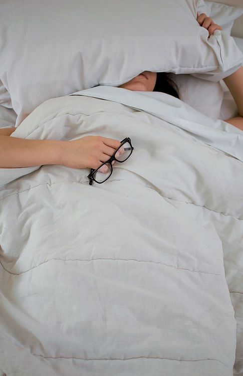 femme-qui-dort-la-tete-sous-l-oreiller-lunettes-a-la-main